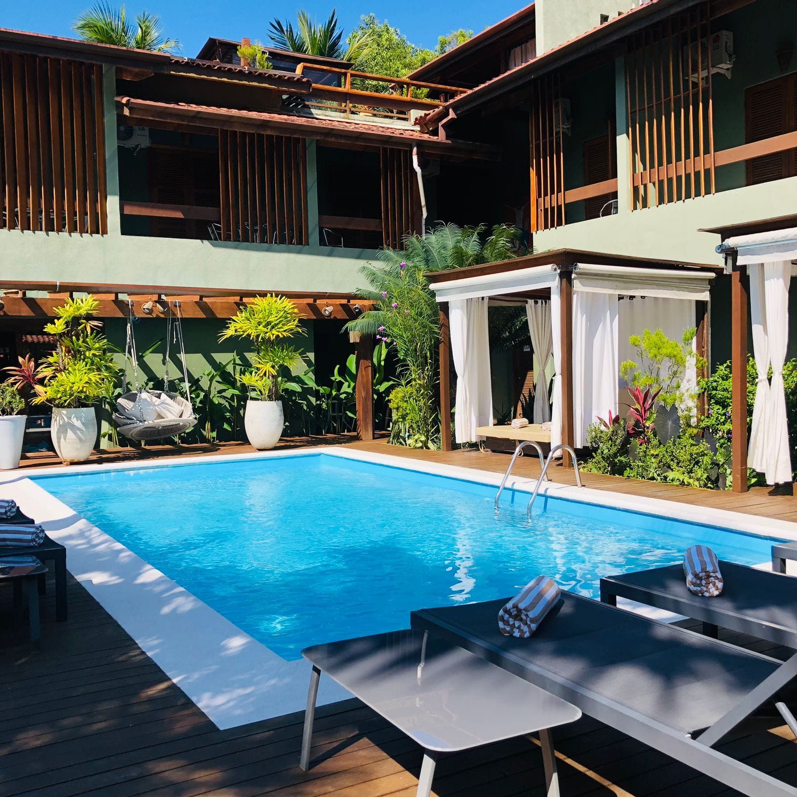 Piscina do Hiu Hotel com espreguiçadeiras e área de lazer